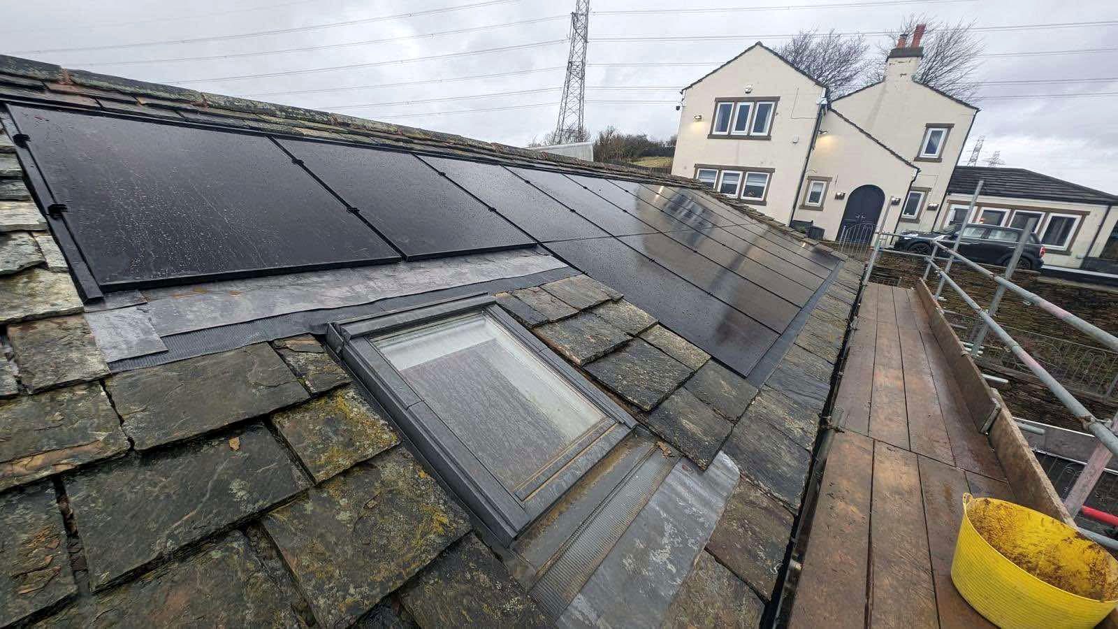 Solar panels installed on a slate roof, with the property behind